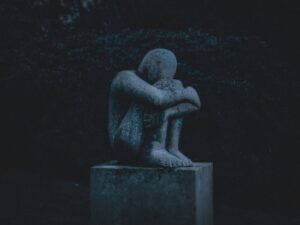 stone carving of a men sitting and hugging his knees