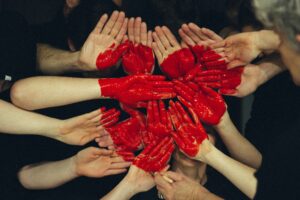 image of hands formed together with red heart paint. For a blog post by Sabrina Walters for Core Values Counseling, Portland, about Valentine's Day.
