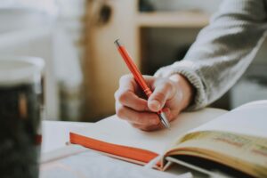 Image of a hand holding a pen and writing in a journal. For a blog post by Sabrina Walters of Core Values Counseling, about self-care without guilt.