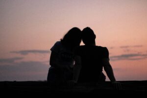 Couple sits closely together outdoors, watching the sunset. For a blog on shared meaning by Eric Walters of Core Values Counseling, Portland.