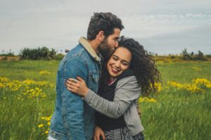 Image of a man kissing the top of a woman's head in a grassy field. For a blog article by Sabrina Walters of Core Values Counseling titled " Don’t Just Repair the Hard Moments — Celebrate the Good Ones"